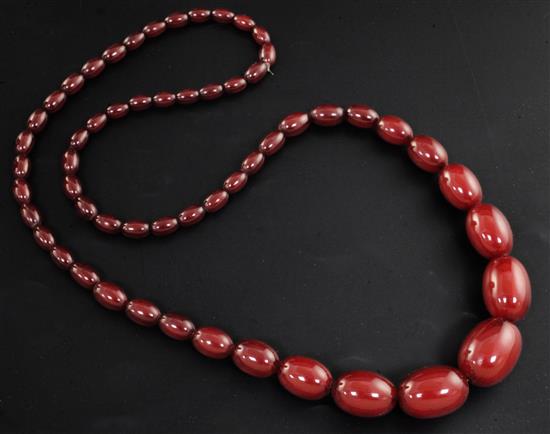 A single strand graduated simulated oval cherry amber bead necklace, 76cm.